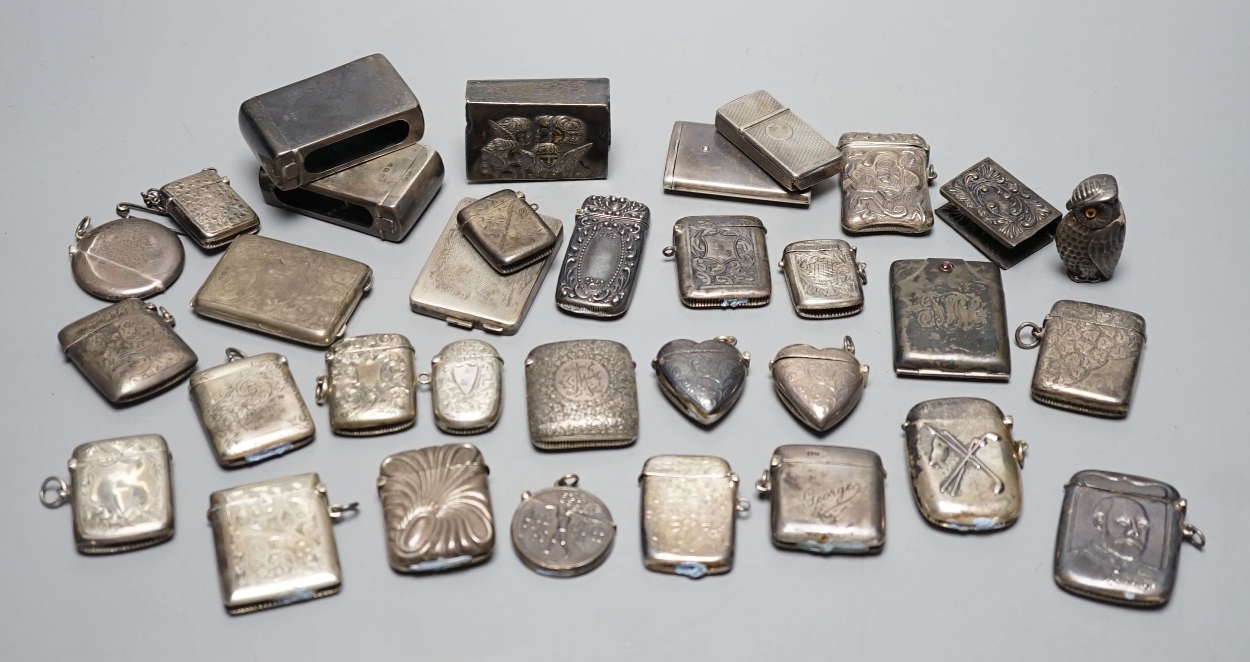 A collection of twenty six assorted mainly early 20th century silver or white metal vesta cases, including heart shape and combination vesta and cheroot cutter, largest 61mm and and seven assorted match cases or sleeves.